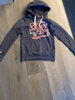 Mörkblå Superdry hoodie med tryck - En superdry hoddie som är i ny skick och väldigt snygg