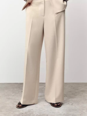 Beige vida kostymbyxor nya zara - Snygga beige kostymbyxor med hög midja och vida ben. Byxorna har pressveck framtill och stängs med dold dragkedja och hake. Tillverkade i ett mjukt, vävt material som ger en lyxig känsla. Perfekta för en clean och stilren look. Ny med prislapp 