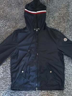Moncler windbreaker - Säljer en snygg marinblå moncler windbreaker i storlek 1. Jackan har använts mycket men i sparsamt skick utan synliga defekter. Kom gärna med prisförslag eller funderingar!