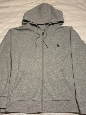 Ralph Lauren zip | Strl M - Snygg och tidlös zip hoodie från Polo Ralph Lauren i klassisk grå färg. 🤩 Mörkblå broderad logga på bröstet.  ✅Storlek M, och är i mycket fint skick ✅Perfekt basic som funkar året runt. Hör av er vid några frågor så löser vi de🤩