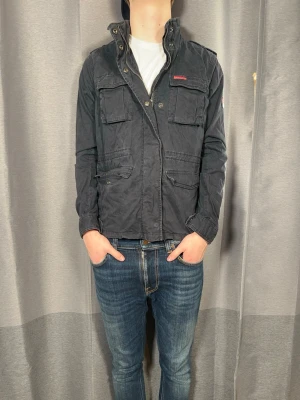 Superdry Fieldjacket  - Tja!| Säljer denna snygga fieldjacket från Superdry!| Mycket gott skick och inga defekter!| Kontakta mig vid minsta fråga!| Pris kan alltid diskuteras! //Nils- Storlek M, men passar xs/s!