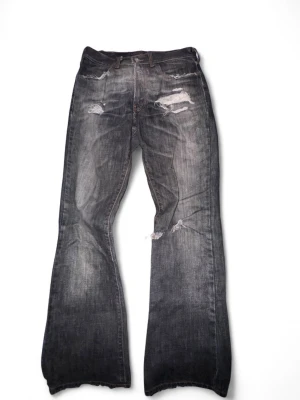 Grå slitna bootcut jeans från fileslondon.com - Säljer ett par grå bootcut jeans med slitningar och hål på låren och knäna. Jeansen har klassisk femficksmodell och en tvättad look som ger en cool vintagekänsla. Perfekta för dig som gillar en avslappnad och trendig stil, liknar ett par Dsquared jeans. Köpte dessa på files London ca 1 år sedan för 300£ ≈ 3500kr men jag måste tyvärr sälja då jag är en fattig student :,)!!!! Hoppas de hittar en ny ägare som uppskattar dem lika mycket som jag… kan ev gå ner LITE i pris vid snabb affär :) 