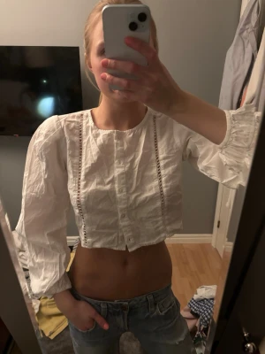 Vit croppad blus med spetsdetaljer - Säljer en vit croppad blus med långa puffärmar och fina spetsdetaljer framtill. Jätte fin till sommaren, använd ett fåtal gånger 
