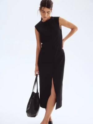 Svart ärmlös långklänning - Stilren svart långklänning med ärmlös design och rak passform. Klänningen har en hög halsringning och är sydd i ett slätt tyg som ger ett elegant intryck. Perfekt för dig som gillar minimalistisk och klassisk stil.