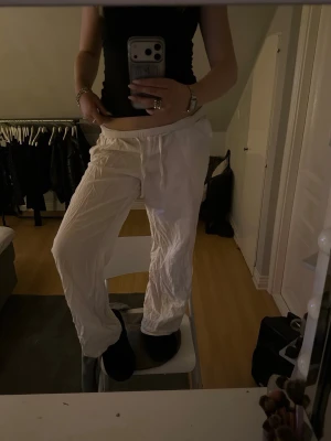 Vita linnebyxor - Säljer ett par vita linnebyxor med avslappnad passform och lite baggy. Byxorna har raka ben och är perfekta för en chill och stilren look. Materialet är lätt och luftigt, vilket gör dem sköna att bära under varmare dagar.