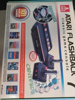 Atari Flashback 7 spelkonsol - Atari Flashback 7 är en retro spelkonsol i svart plast med klassisk design och röda detaljer. Konsolen har 101 inbyggda spel, inklusive Frogger och Centipede, och levereras med två joystick-kontroller. Perfekt för dig som gillar klassiska arkadspel.