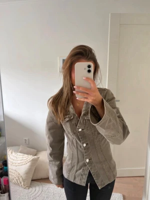 Khaki figursydd jeansjacka Gina - Snygg khaki jeansjacka med figurnära passform och markerade sömmar. Köpt ifrån Gina tricot och är i storlek xs.💕 Säljs då den är för stor!
