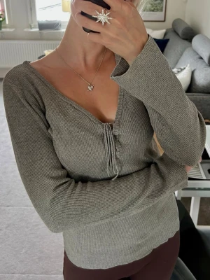 Grå ribbad långärmad topp - Grå ribbad topp med lång ärm och v-ringning med snörningsdetalj framtill🥰🥰