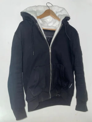 Moose knuckles bunny - Säljer en svart hoodie från Moose Knuckles med dragkedja, stora fickor och vit fluffig foder i huvan som sträcker sig ner längst dragkedjan på insidan, päls går att plocka av och på.