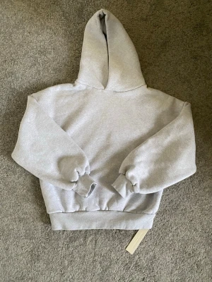 Ljusgrå hoodie från Velour Garments - Snygg ljusgrå hoodie från Velour Garments med klassisk huva och breda muddar vid ärmslut och midja. Längden på hoodien är 62 cm och brädden 58 cm. Priset kan diskuteras! Har haft på mig den bara en gång hemma!