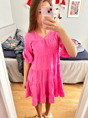 Rosa volangklänning med v-ringning - Supersöt rosa klänning med v-ringad hals och volangdetaljer. Den är lite stickig.