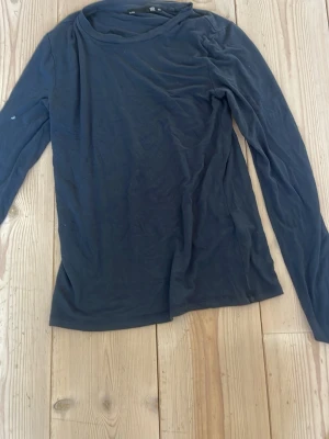 Mörkblå långärmad topp laget  157 - En enkel och stilren mörkblå långärmad topp från lager 157. Tillverkad i mjuk bomull med rund halsringning och normal passform. Perfekt att matcha med jeans eller kjol för en clean look.