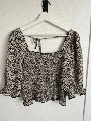 Blommig croppad blus - Blus från H&M i storlek s med croppad passform och puffiga trekvartsärmar. 