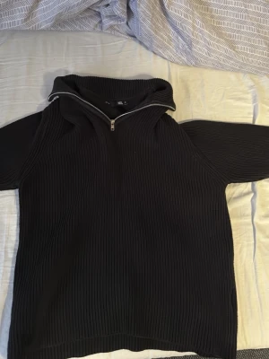 Half Zip Tröja - Säljer en svart ribbad stickad tröja från Lager 157 med hög krage och half zip-dragkedja. Tröjan har lång ärm och en oversized passform som ger en chill vibe. Perfekt för kalla dagar när du vill vara både bekväm och snygg. I princip oanvänd. Fraktas endast och köparen står för frakt.