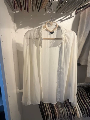 Vit blus med spetsdetaljer - Söt vit blus från Gina Tricot med långa ärmar och fina spetsdetaljer vid krage och ärmslut. Blusen har knappar vid manschetterna och är gjord i ett tunt, lätt material som ger ett romantiskt intryck. Perfekt att styla med jeans eller kjol.