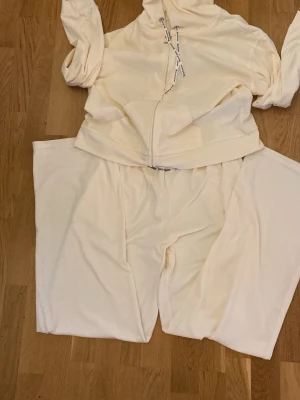 Krämvitt Juicy Couture loungewear-set - Helt nytt ny pris 1500 Mysigt loungewear-set från Juicy Couture i krämvit velour. Setet består av en zip-hoodie med dragkedja och matchande byxor. Hoodien har detaljer med Juicy Couture-tryck på snörena och en metallisk J-dragkedja. Perfekt för chill dagar hemma. Pris kan diskuteras 