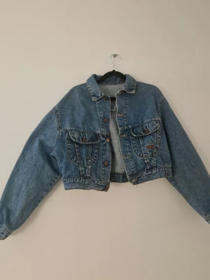 Croppad ljusblå jeansjacka - Äldre ljusblå croppad jeansjacka med boxig fit. Passar både S och M. Har några lösa trådar annars i mycket bra skick.