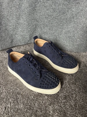 Mörkblå sneakers med nitar Louboutin - Snygga mörkblå sneakers från Christian Louboutin med nitar. Alla nitar finns kvar!     Storlek 41. 8/10 skick!