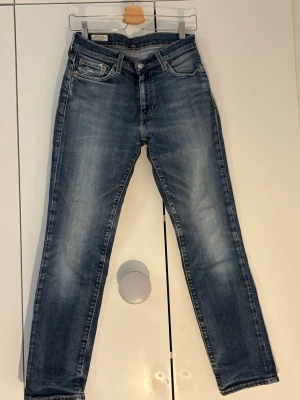 Blå Levi's 511 slim jeans - Säljer ett par klassiska blå Levi's 511 slim jeans med snygg tvätt och lätt slitna detaljer. Jeansen har fem fickor, knappgylf och normal midja. Tillverkade i bomull med en liten mängd stretch för extra komfort. Perfekta för en avslappnad och trendig look.