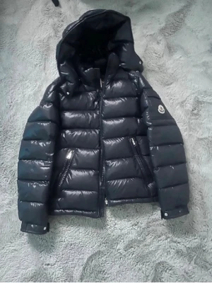 Moncler jacka - Äkta Snygg dunjacka från Moncler för någon som e runt 155cm köpt för 8000kr med glansig finish och stor huva. Jackan har två framfickor med dragkedja och Moncler-logga på ärmen. Perfekt för kalla vinterdagar och ger en riktigt trendig look.