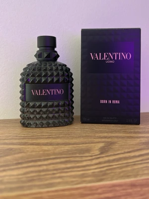 Valentino Uomo Born In Roma EdT 80-90ml - Valentino Uomo Born In Roma EdT är en exklusiv herrparfym i en svart, nitat glasflaska med matchande svart kartong. Flaskan har en unik, lyxig design med pyramidformade detaljer och tydlig Valentino-logga. Doften är modern och elegant, perfekt för dig som vill sticka ut.