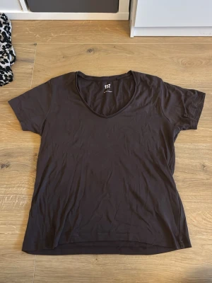 Mörkbrun basic t-shirt - En enkel mörkbrun t-shirt med rund halsringning och korta ärmar. Modellen är rak och materialet ser ut att vara mjukt och bekvämt, troligen bomull eller bomullsblandning. Perfekt till jeans eller shorts för en avslappnad look.