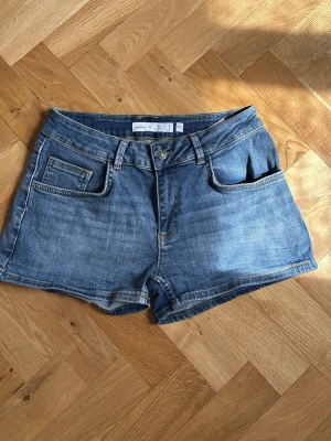 Blå denimshorts från Subdued - Säljer ett par klassiska blå denimshorts från Subdued med låg midja och snygga bakfickor med gul söm i fin detalj ☺️. Shortsen har bälteshällor, knapp med logga och är perfekta för sommaren ☀️. Dessa shorts har bara används en gång dersom priset ❤️🤗. 