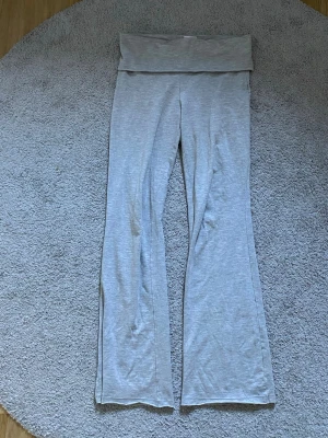 Grå leggings från Gina Tricot - Snygga grå leggings från Gina Tricot med bootcut-modell och bred midjeresår. Mjukt och stretchigt material som sitter skönt hela dagen. Perfekta för en avslappnad och trendig look. Passar strl xs