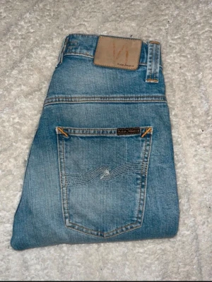 Nudie jeans  - Ljusblåa jeans från Nudie Jeans i modellen Tape Ted. Midja 32cm, längd 105cm. JAG SKICKAR EJ FLER BILDER NÄR JAG BÄR JEANSEN! för bättre inblick i passformen rekommenderar jag att googla på modellnamnet. För storleksguide kolla måtten noggrant då jeansen alltid kan vara uppsydda heller krympta och jag ej tar emot returer :) s6,5