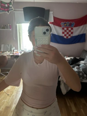 Ljusrosa omlottopp med knyt - Supersöt ljusrosa omlottopp med knyt i ryggen och korta ärmar. Toppen har en mjuk och flowy passform och är perfekt för en trendig och feminin look. Passar till både kjol och jeans för en söt outfit.
