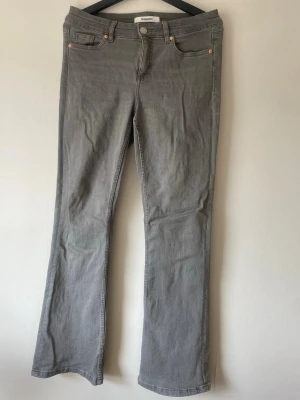 Gråa flare jeans från Kappahl - Säljer ett par gråa flare jeans från Kappahl med låg midja. med utsvängda ben och snygga detaljer. 