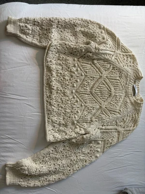 Stickad tröja från Zara - Säljer en beige stickad tröja med grovt strukturmönster och unika detaljer. Tröjan har rund halsringning, långa ärmar och ribbade muddar. Perfekt för dig som gillar en cozy och trendig look köpare står för frakt.