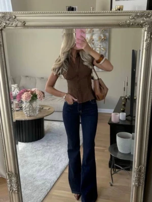 Mörkblå bootcut jeans - Säljer ett par mörkblå bootcut jeans med midwaist midja och klassisk femficksdesign. Jeansen har en snygg utsvängd passform som ger en retrovibe och passar perfekt till både skjorta och stickad tröja. Materialet är denim med lätt stretch för extra komfort. Sprättat längst ner men inget som syns på byxorna 