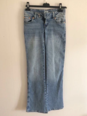 Ljusblå bootcut jeans med brodyr - Säljer ett par ljusblå bootcut jeans med snygg broderad detalj på bakfickorna. Low waist, aldrig använda men prislappen är borta eftersom jag trodde jag skulle använda de. Lite dåliga bilder💕