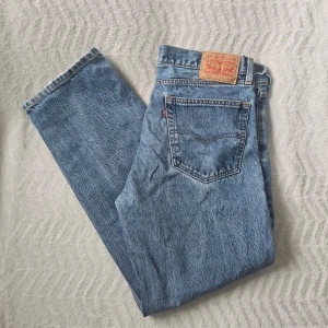 Levi's 505 blå raka jeans - Klassiska blå Levi's 505 jeans med rak passform och hög midja. Jeansen har fem fickor, knappgylf och den ikoniska läderlappen bak i midjan. Tillverkade i slitstark denim med vintage vibe och snygg tvätt.