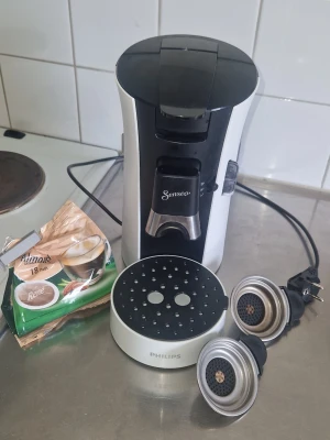 Senseo kaffemaskin från Philips - Fungerar felfritt. Kan brygga 1 eller 2 koppar samtidigt. Två kapselhållare ingår: en för 1 kapsel och en för 2 kapslar så man kan variera styrka och mängd. En kapsel = en kopp/2 mindre koppar, två kapslar = starkare kaffe eller två koppar beroende på hur man brygger. Lite kalkfläckar finns trots rengöring då vi bor i kalkrikt område, men går att få bort med avkalkning, icke-kalkvatten eller rengöringsspray-går använda utan problem ändå. Medföljer en påse kaffe med smak av mandel, bara tagit en.