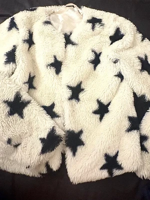 Vit teddyjacka med svarta stjärnor - Hittar ingen storleksangivelse men skulle tro xs!! Supermjuk teddyjacka i vitt med stora svarta stjärnor över hela plagget. Jackan har rund halsringning och är helfodrad för extra komfort. Perfekt för dig som vill sticka ut med en unik och trendig look.