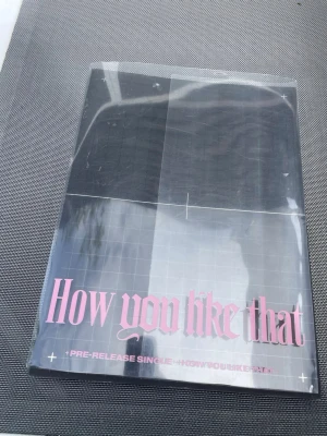 How You Like That fotobok Blackpink - Säljer en fotobok med titeln 'How You Like That' från BLACKPINK. Boken har ett svart och rosa omslag med modern design och innehåller färgstarka bilder på medlemmarna. Perfekt för fans av K-pop och BLACKPINK.