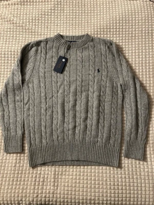 Grå kabelstickad tröja Polo Ralph Lauren - Säljer en grå kabelstickad Ralph Lauren tröja i storlek S. Kvitto finns!  Hör av dig om du har frågor eller prisförslag