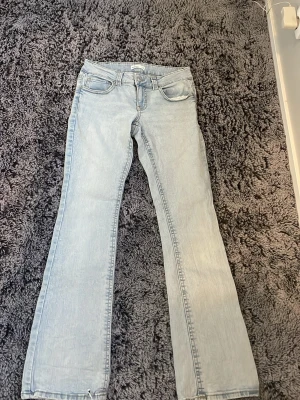 Ljusblå bootcut jeans - Snygga ljusblå bootcut jeans med klassisk femficksdesign och låg midja. Jeansen har en lätt tvättad look och vida ben nedtill. Perfekta för en avslappnad och trendig stil. Materialet är denim i bomull.