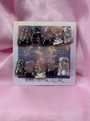 TenshiNoir (XS);Medium Duck Nails - Unika handgjorda duck press-on naglar i nuderosa och svart med coola 3D-metalldekorationer som stjärnor, säkerhetsnål och ringar. Korta Duck nail form och detaljer i silver ger en edgy och trendig look. Perfekt för dig som vill sticka ut med dina naglar.XS: 14 mm, 11 mm, 11,5 mm, 10 mm, 8 mm 
