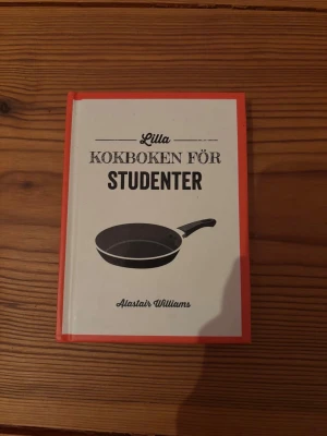 Lilla kokboken för studenter - Kokbok med hårda pärmar i vitt och rött, skriven av Alastair Williams. Perfekt för studenter som vill laga enkel och god mat. Boken har illustration av en stekpanna på framsidan och innehåller lättlagade recept och smarta tips för köket. Aldrig använd men ej förpackning kvar.