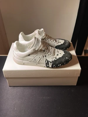 Intressekoll! - Intressekoll på dessa maison margiela gats. Dom har black paint splatter och är i 9/10 skick med små skavanker dom inkluderar box dustbag och sko skydd!
