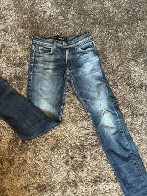 Blå slim fit jeans från Replay - Snygga blå slim fit jeans från Replay med klassisk femficksdesign och slitningar på låren. Jeansen har normal midja och är tillverkade i denim med lätt stretch för skön passform. Perfekta för en avslappnad och trendig look.