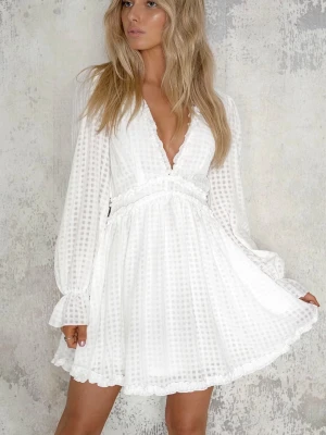 Studentklänning - Superfin vit kortklänning från Dennis Maglic med långärmade puffärmar, volangdetaljer och öppen rygg. Klänningen har ett diskret rutigt mönster i tyget och knappar i nacken. Jätte gullig och passar som perfekt som studentklänning !! Storlek L och helt ny med prislappen på. Nypris 899 kr   Första 2 bilderna är framsidan, 3-5 är baksidan och sista bilden är bevis på att den ej är använd.   Länken till klänningen är https://dennismaglic.com/sv/products/veronica-dress  , så man kan se bättre bilder 