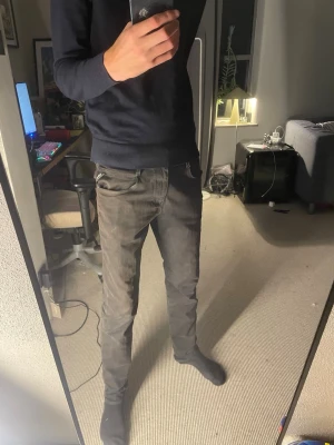 Svarta Replay jeans - Säljer ett par svarta slim fit jeans med klassisk femficksdesign och dragkedjegylf. Jeansen har en snygg tvättad look och smal passform som sitter tajt längs benen. Perfekta för en stilren och avslappnad outfit. Från Replay 