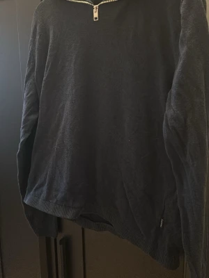 Mörkblå halvzip tröja - En stilren mörkblå tröja med halv dragkedja vid halsen. Tröjan har långa ärmar och ribbade muddar vid ärmslut och nederkant. Perfekt för lager på lager och enkel att matcha med olika outfits. Ny pris 500kr