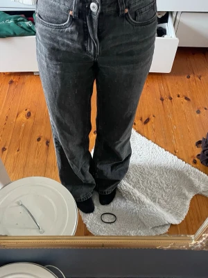 Svarta raka jeans med hög midja - Säljer ett par svarta raka jeans med hög midja och klassisk femficksmodell. Jeansen har en avslappnad passform och är tillverkade i denim. Perfekta för en cool och enkel stil.