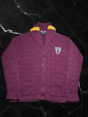 Vintage Ralph Lauren kabelstickad kofta - herr strl XL  - Säljer en vintage Ralph Lauren kabelstickad kofta i vinröd färg med mörkgula detaljer vid kragen i storlek XL. Broderad Ralph Lauren sköld på vänster sida av bröstkorgen.  👕 Märke: Ralph Lauren 📏 Storlek: XL 🎨 Färg: Vinröd med mörkgula detaljer vid kragen 🧵 Material: 95% bomull, 5% cashmere 📐 Mått: 71 cm lång, 59 cm bred 📌 Skick: Mycket bra skick (se bilder)  💬 Hör av dig vid frågor 💰 Pris kan diskuteras vid snabb affär 📦 Skickas inom 24 timmar