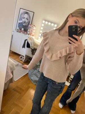 Ljusrosa stickad tröja  - Säljer en ljusrosa stickad tröja med snygg volangdetalj. Perfekt för dig som gillar feminina detaljer och mjuka färger. 
